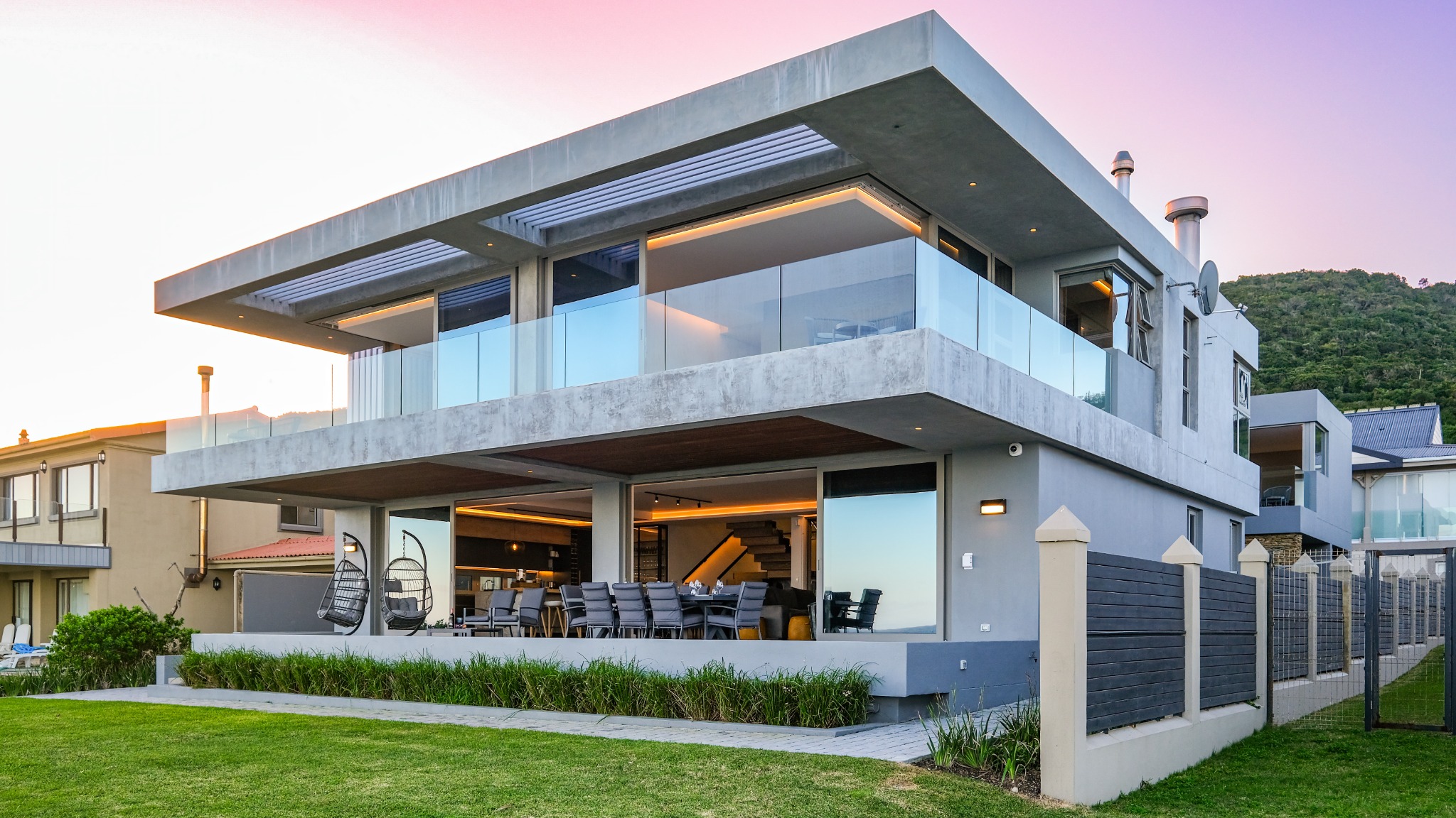 Modern coastal home with glass balconies at sunset